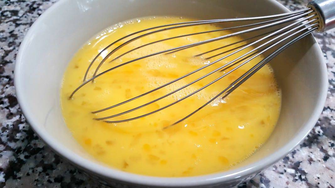 eggs, milk, and salt mixed in a bowl with a whisk for baked omelets.