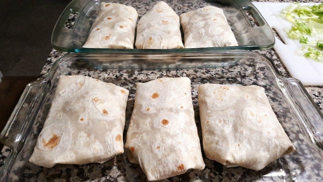 two baking dishes, each has 3 rolled up burritos in it
