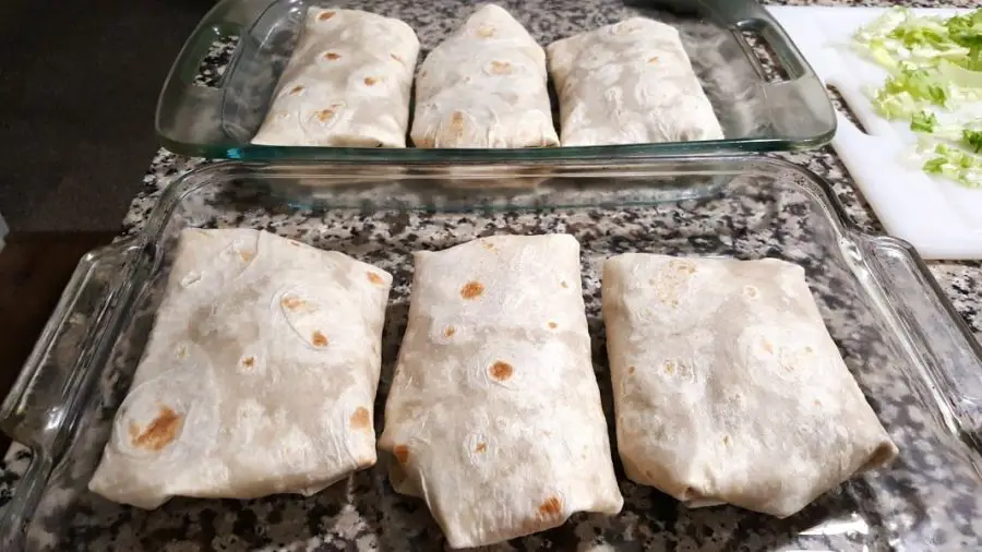 two baking dishes, each has 3 rolled up burritos in it.