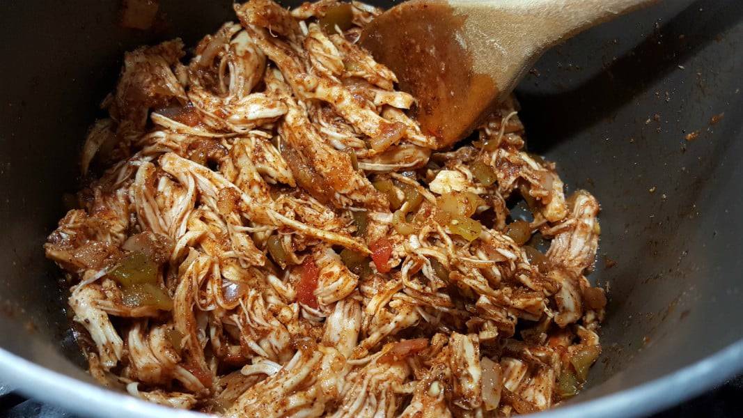 shredded chicken, salsa, brown sugar, spices, and liquid smoke mixed together and cooking in a sauce pan.