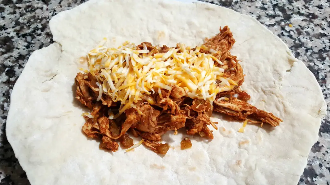 chicken chimi mixture topped with cheese on a burrito size tortilla.