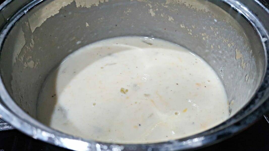 cheesy Chimichanga White Sauce cooking in a sauce pan.