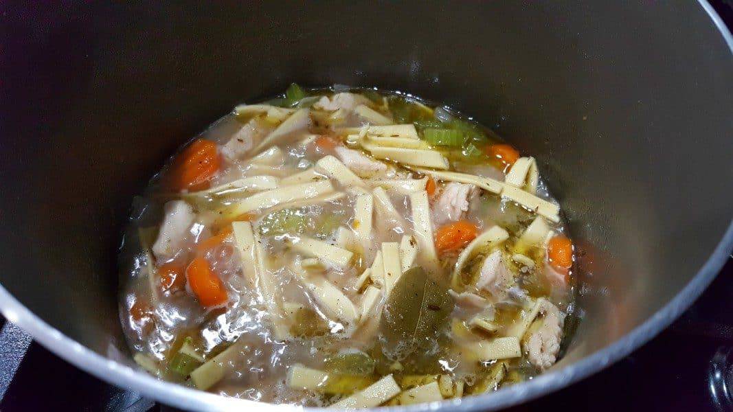 chicken noodle soup cooking in a large sauce pan