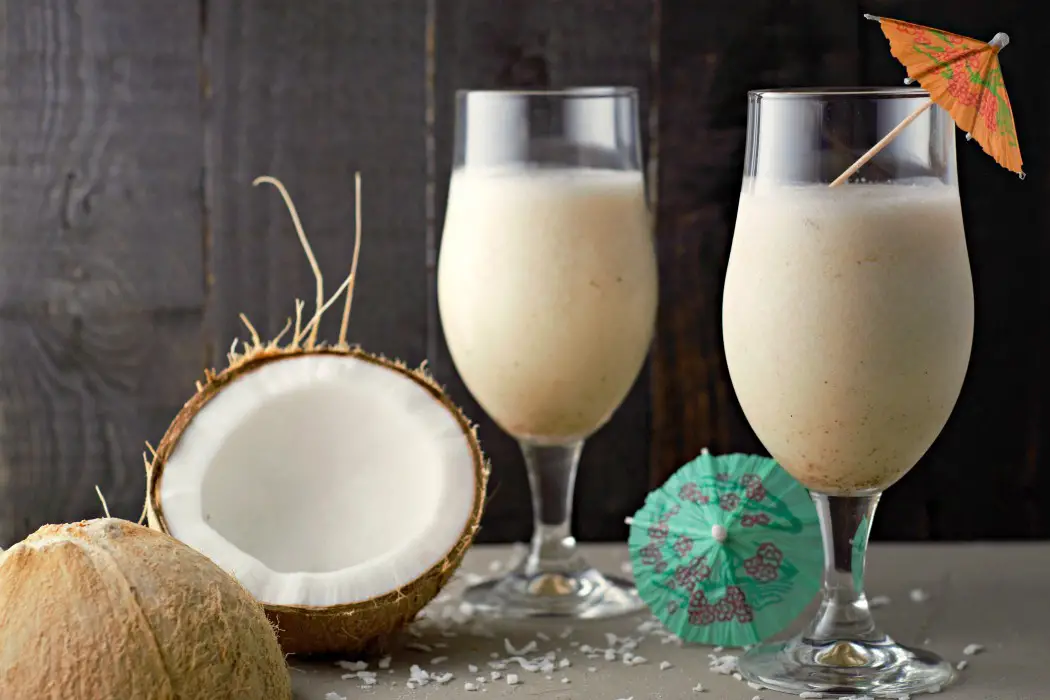 Two easy Pina Coladas for two with Bacardi rum and sweetened condensed coconut milk pictured with a sliced open coconut