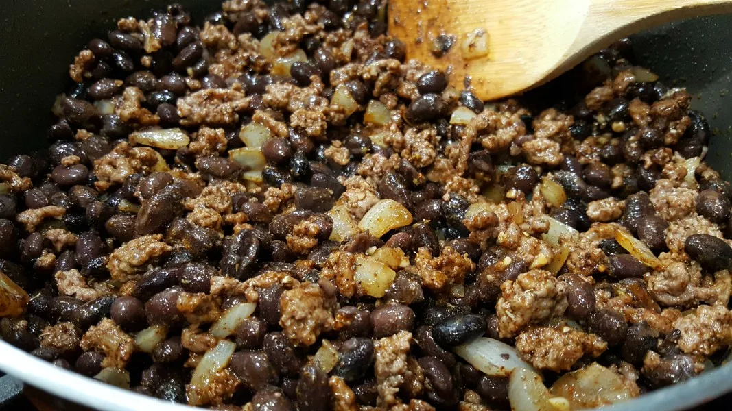 cooking ground beef, onion, black beans, and spices in a skillet.