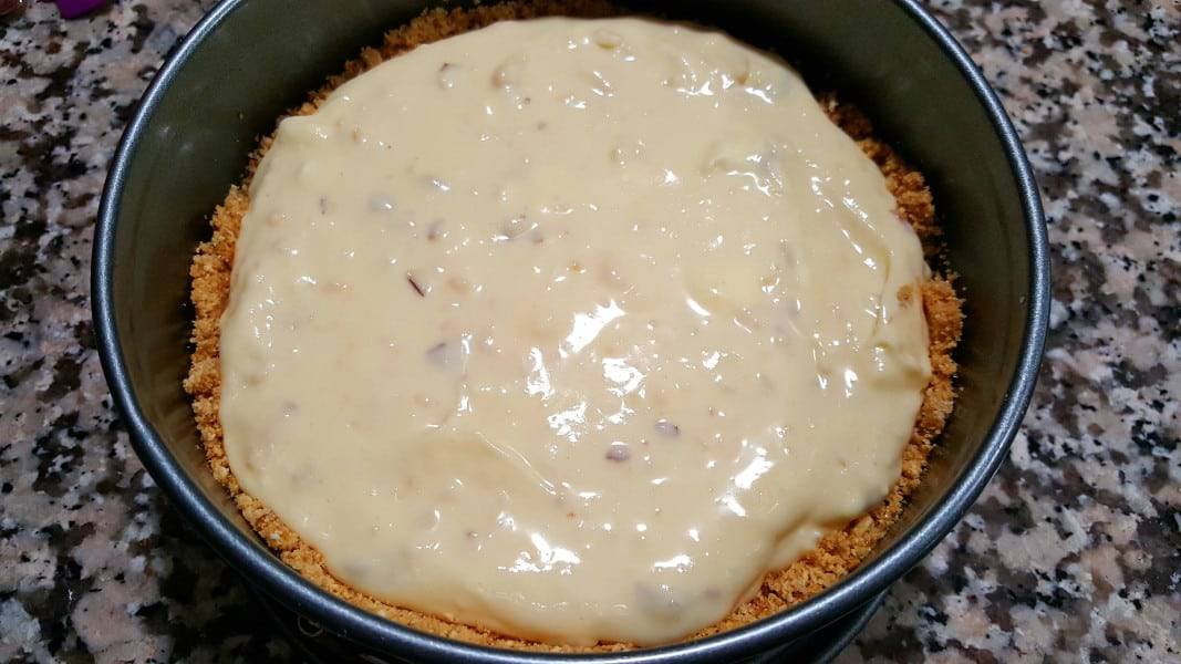 a springform pan with graham crust and amaretto cheesecake batter inside.