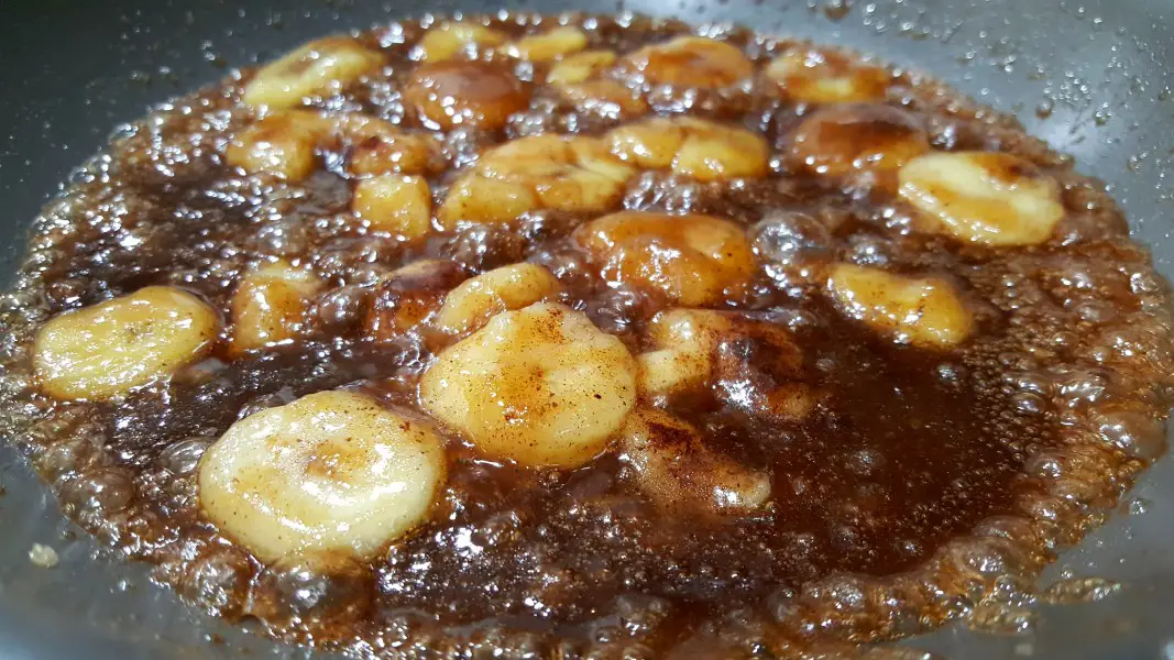 caramelized bananas cooking in a frying pan.