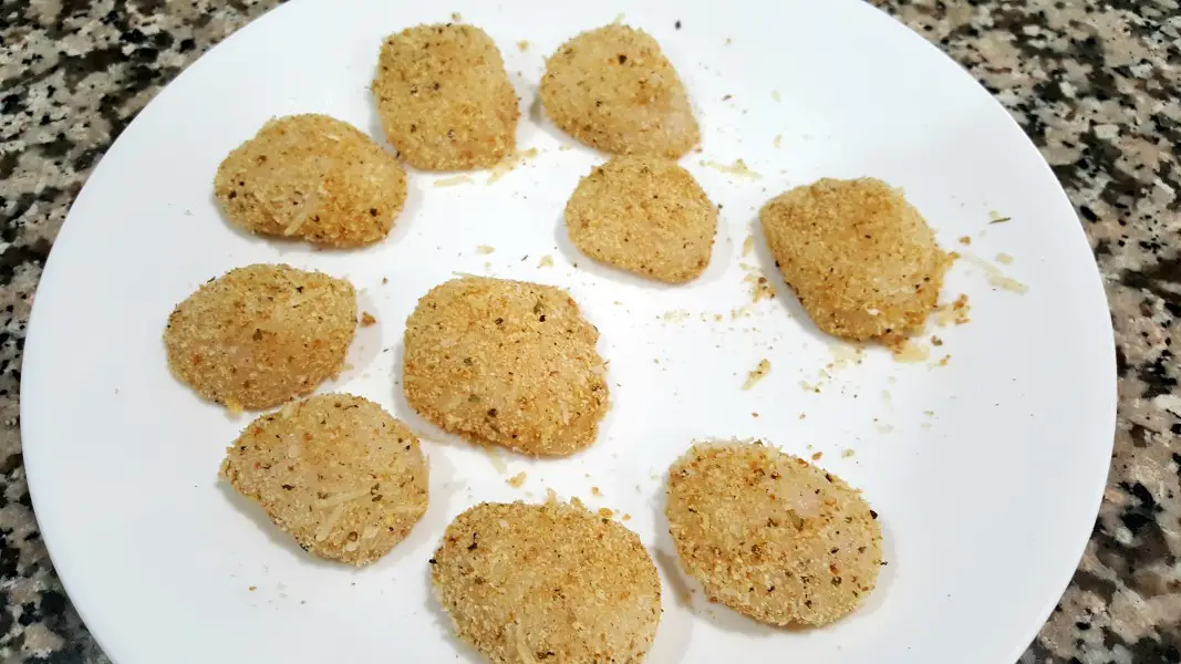 sea scallops coated in bread crumb mixture on a plate.