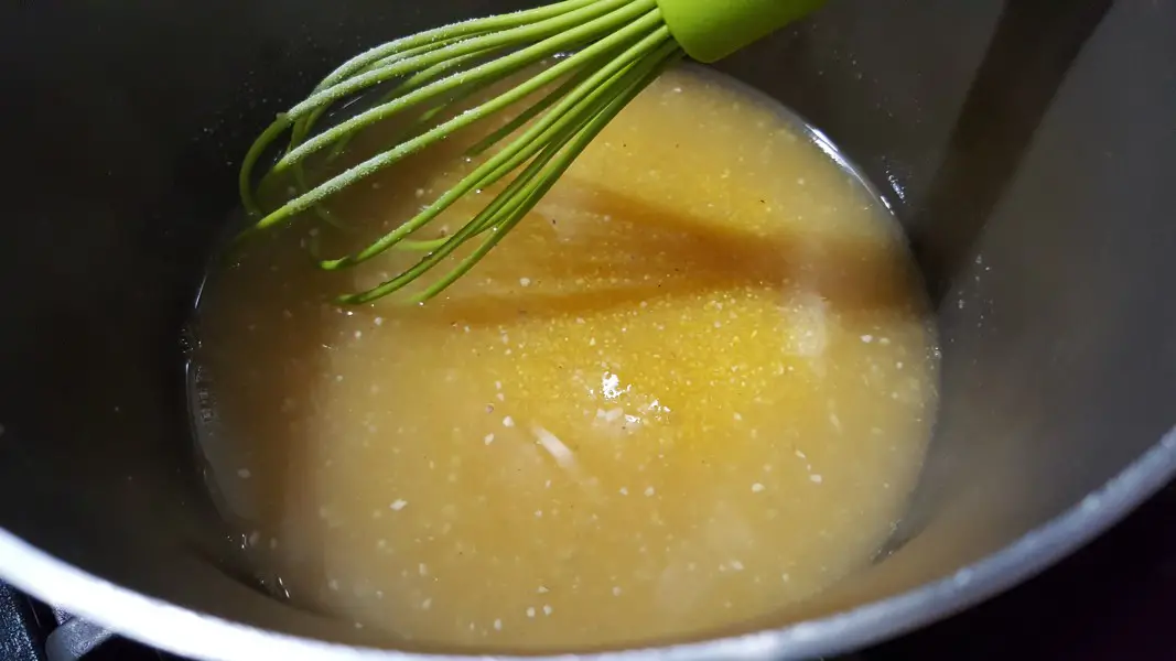 polenta simmering in chicken stock in a sauce pan.