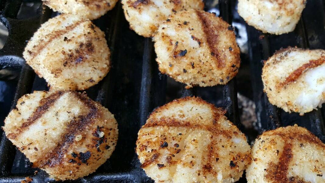 breaded sea scallops cooking on a grill.