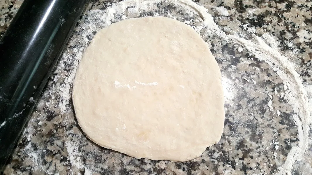 pizza dough rolled out into a circle.