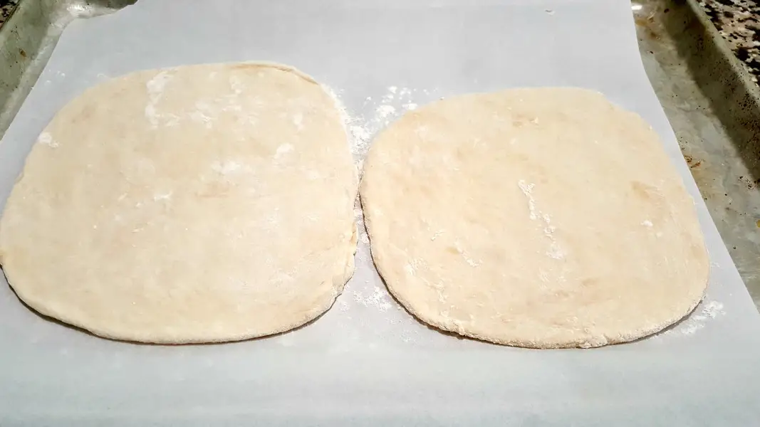 to circles of pizza dough on a baking sheet.