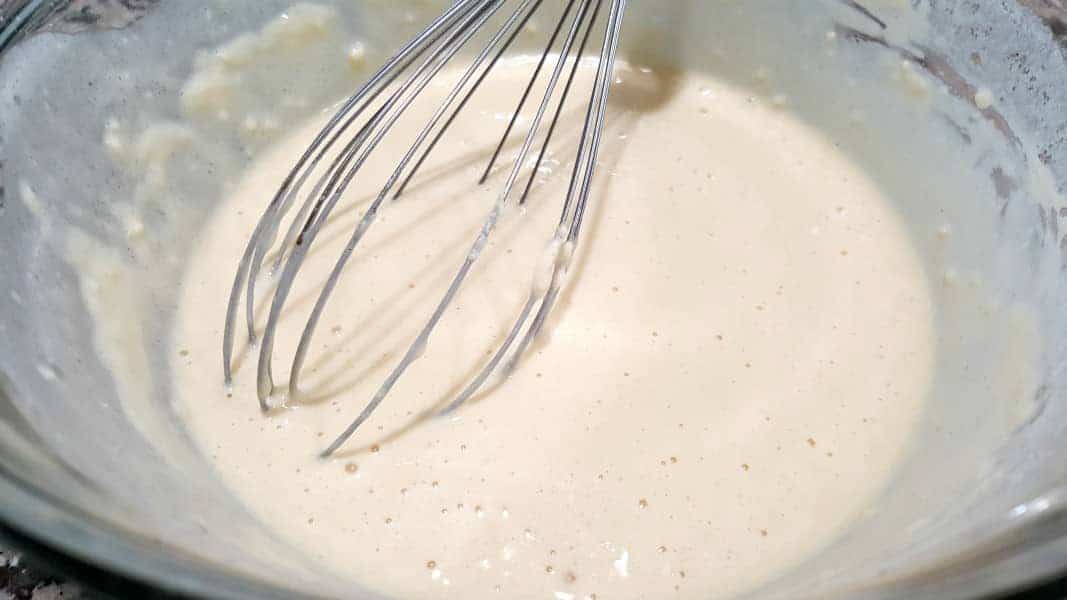 Belgian waffle batter in a bowl with a whisk