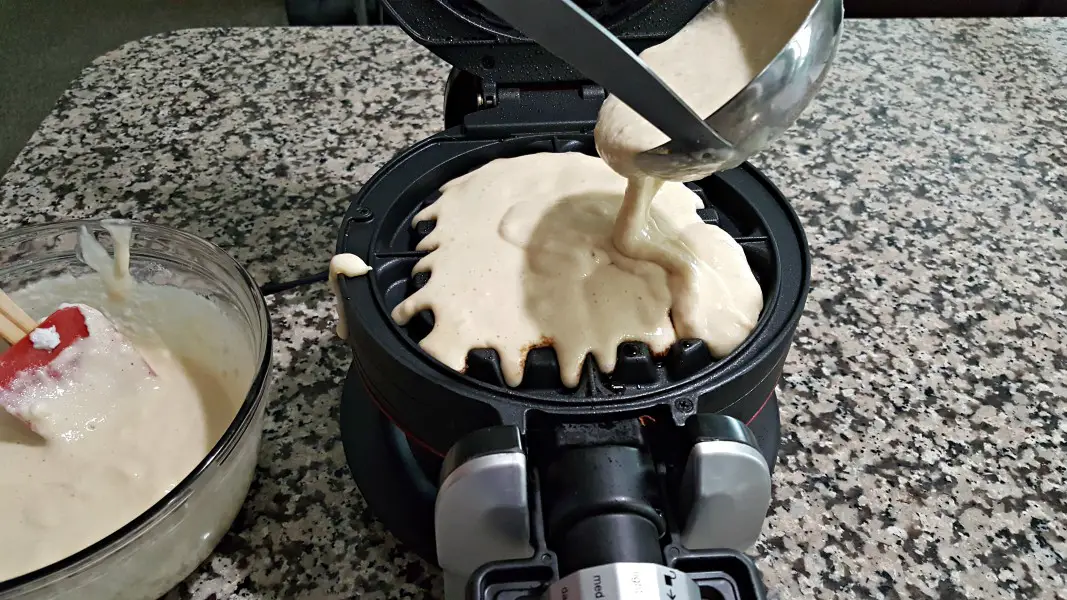 pouring waffle batter into the first side of the waffle iron.