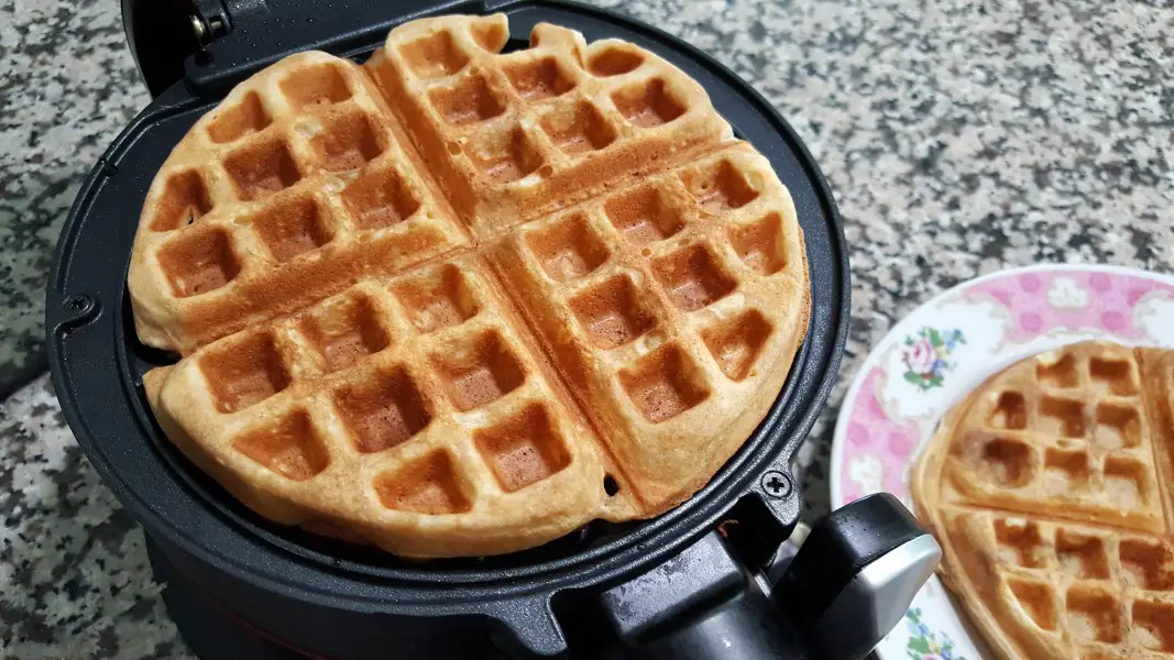 Thick and Fluffy Waffles in the iron and a plate with second waffle.