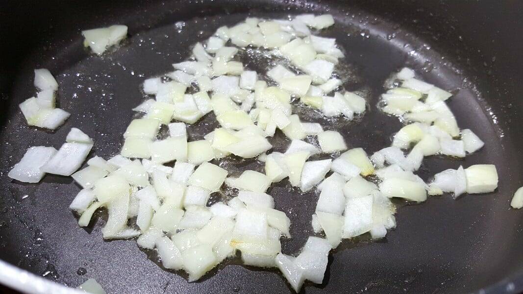 diced onion cooking in a skillet for swedish meatballs.