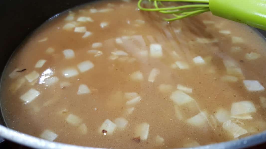 beef broth and onion gravy cooking in a skillet.