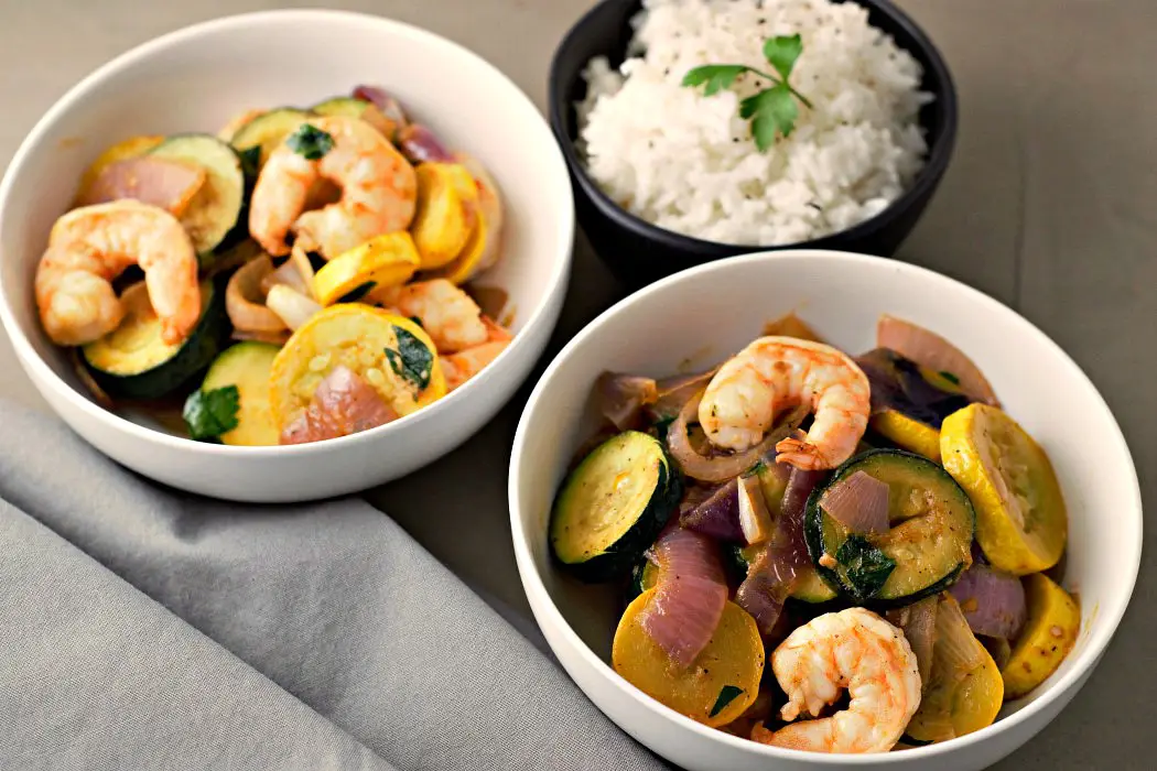 Garlicky Shrimp Zucchini in two bowls with a side of rice.