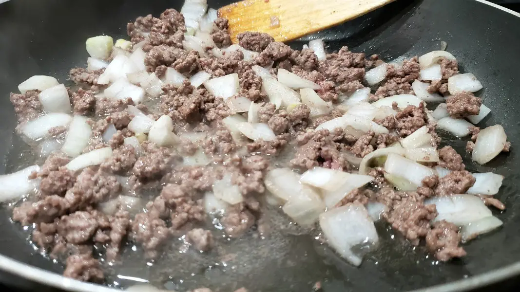 ground beef and onions cooking in a pan.