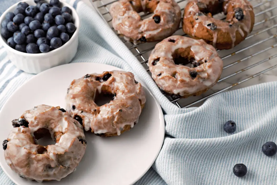 best Glazed Blueberry Cake Donuts with old fashioned blueberry donuts on a plate and rack.