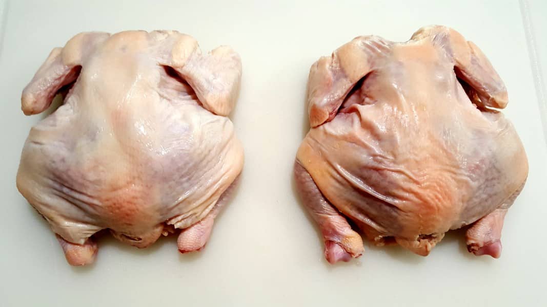 two raw Cornish game hens on a cutting board.