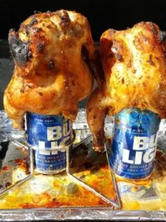 two Grilled Beer Can Cornish Hens cooking on a grill.