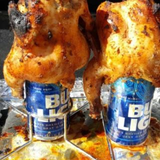 two Grilled Beer Can Cornish Hens cooking on a grill.