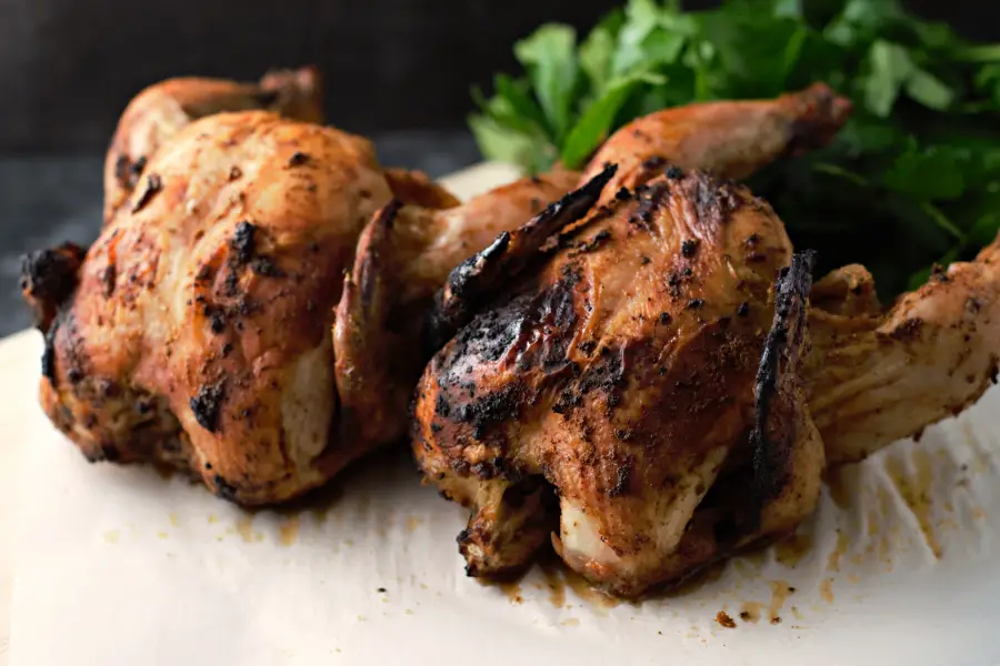 two Grilled Cornish Hens on parchment paper.
