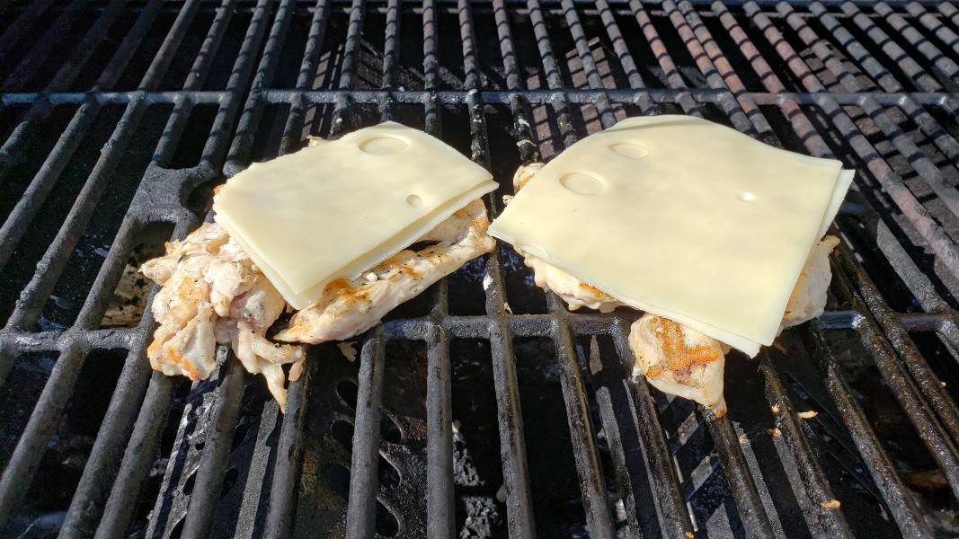 two pieces of grilled chicken topped with Swiss cheese
