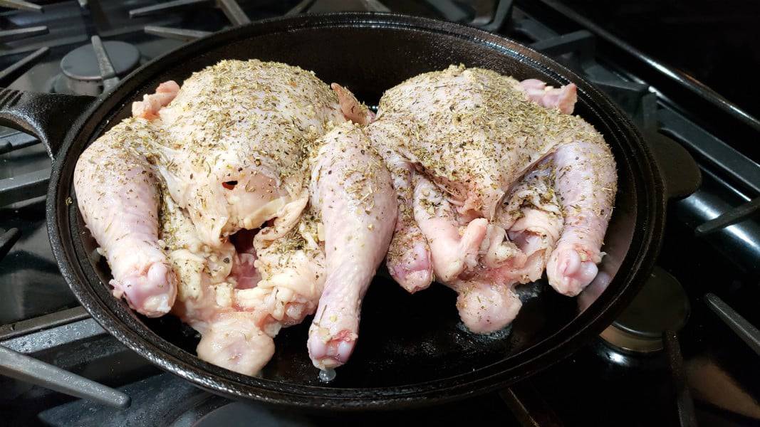 two herb covered cornish hens in a cast iron skillet.