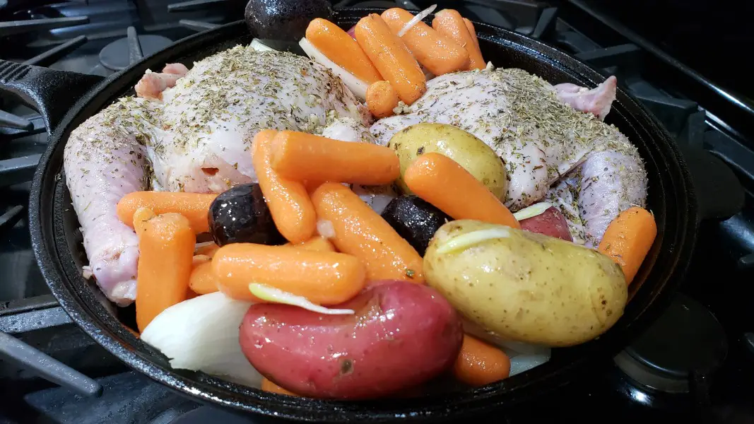 unbaked cornish game hens and vegetables in a cast iron skillet.