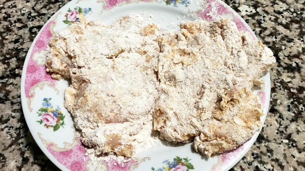 two chicken pieces coated in egg and flour mixtures.