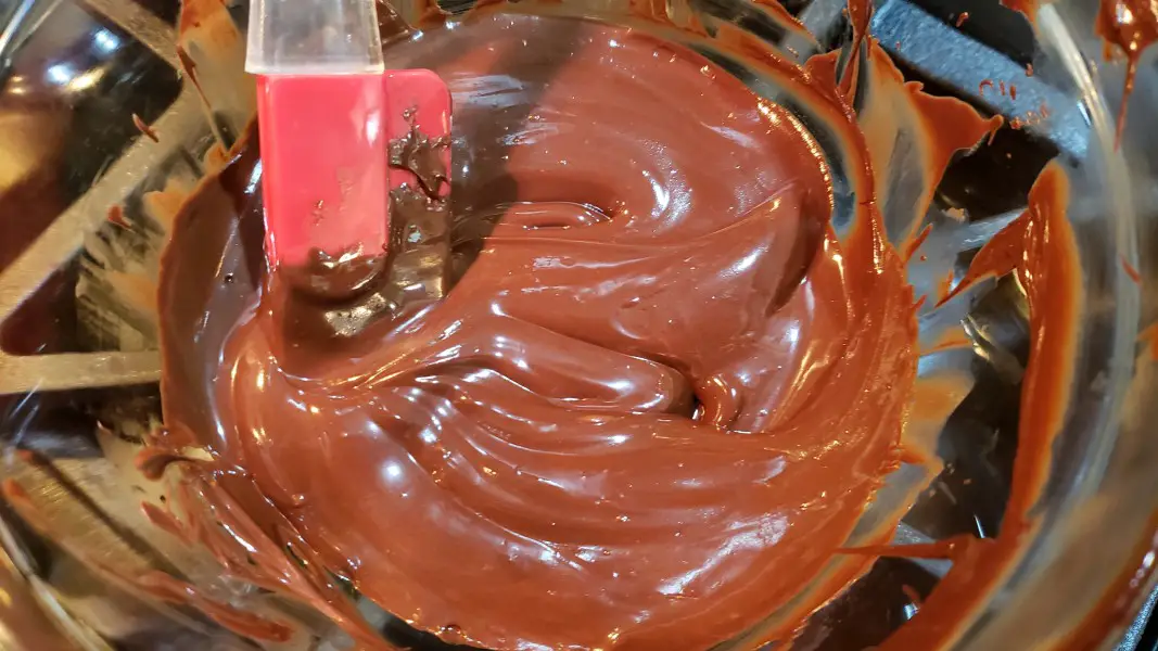 melted chocolate in a bowl with red spatula.