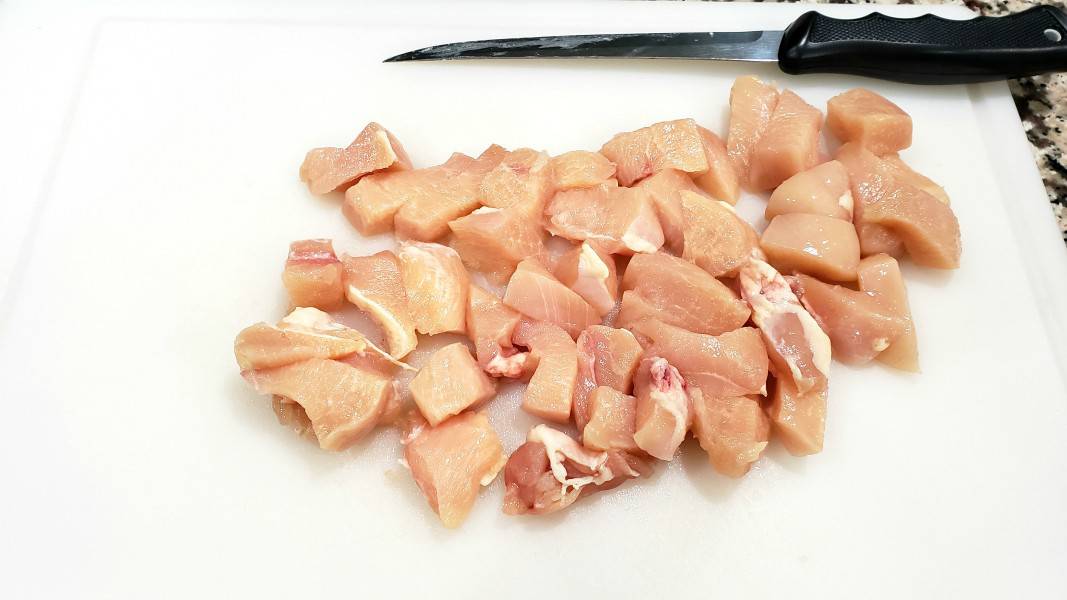 bonless chicken diced on a cutting board.