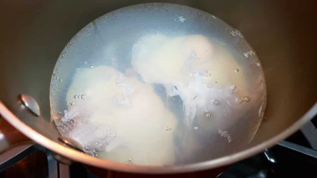 two eggs poaching in a pan.