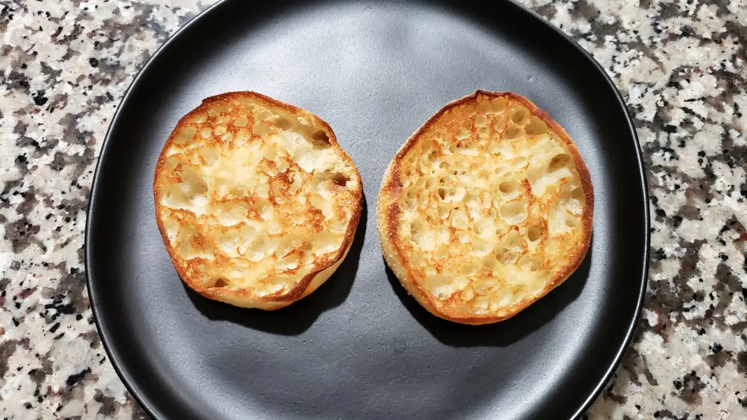 two halves of a toasted english muffin on a plate.