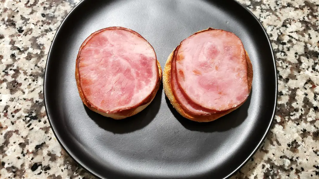 english muffin halves topped with two slices canadian bacon each.