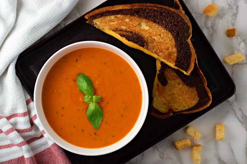 Homemade Garden Fresh Tomato Soup from scratch in a bowl with a grilled cheese sandwich.