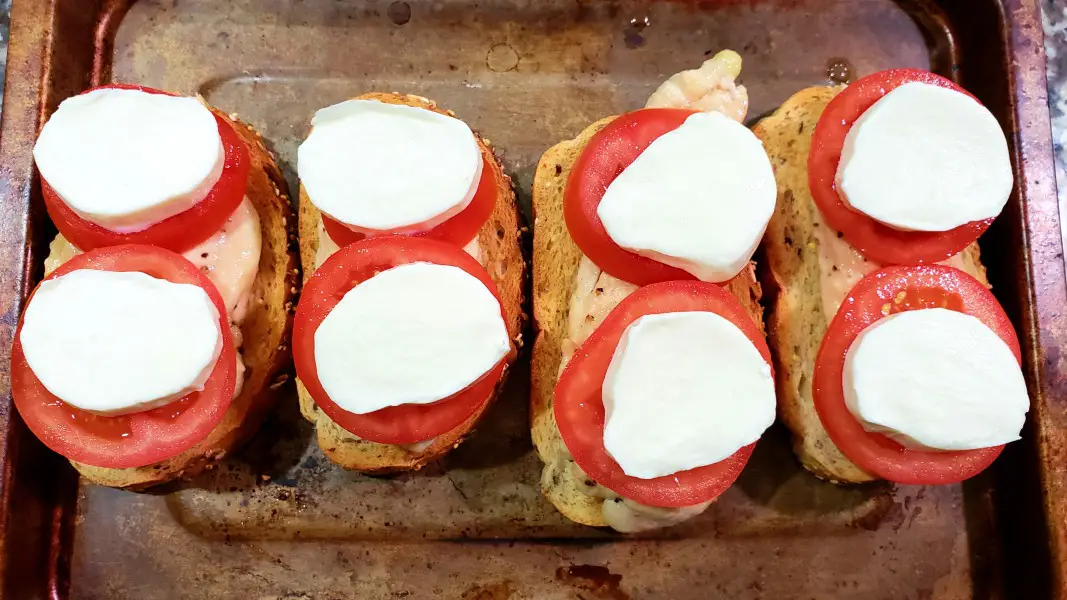 toast, chicken, and tomatoes topped with mozzarella slices.