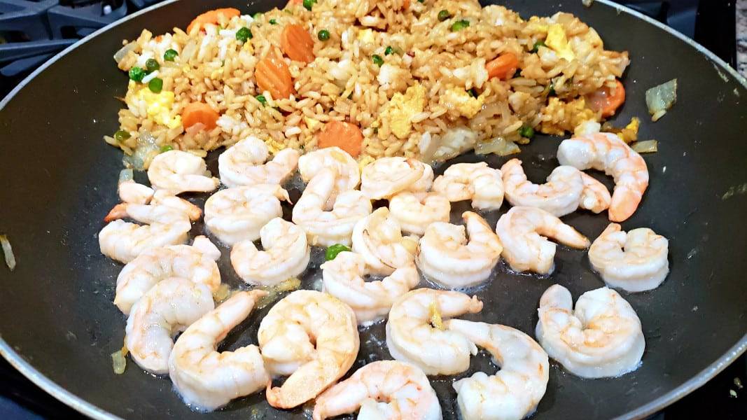 shrimp cooking in a pan with fried rice.
