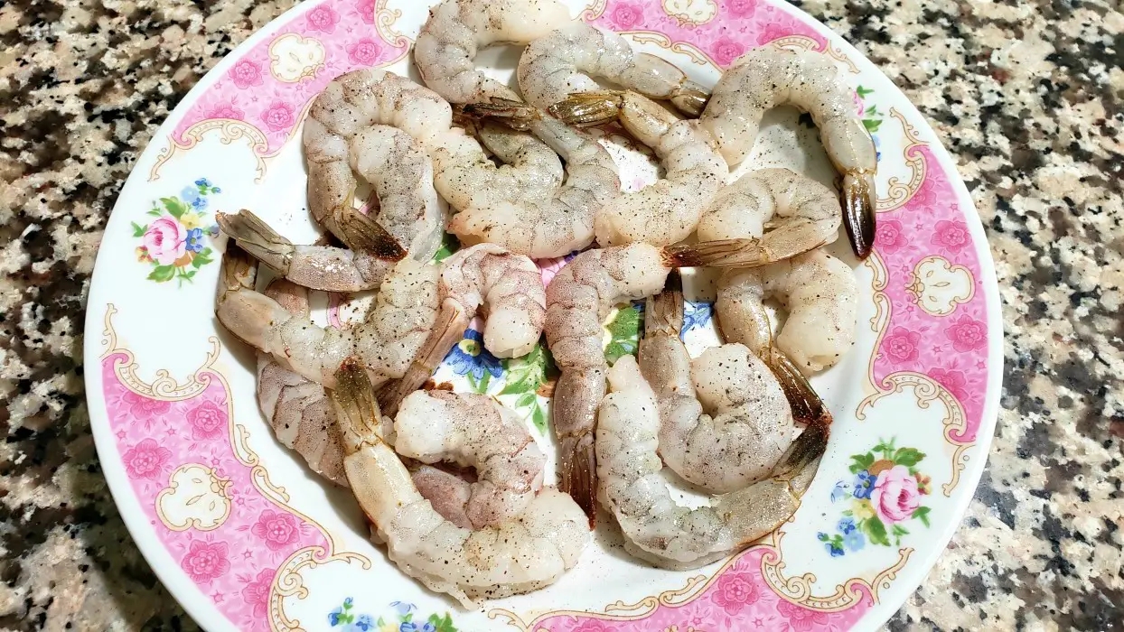 raw shrimp sprinkled with pepper on a plate.