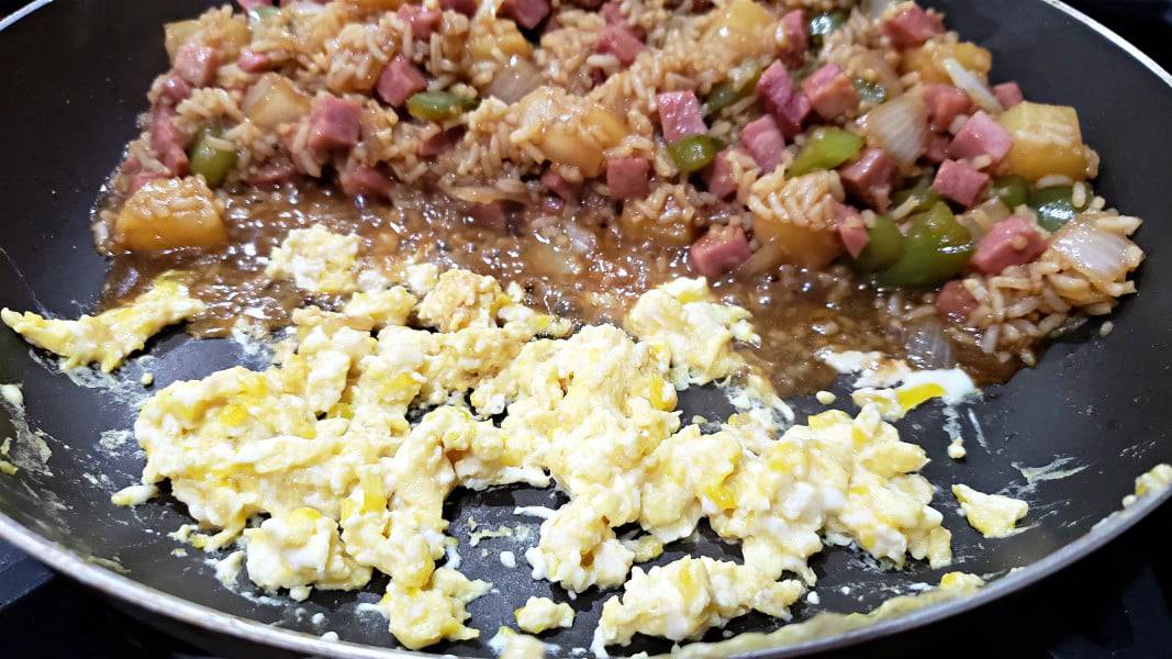Hawaiian fried rice and scrambled egg cooking in a pan.