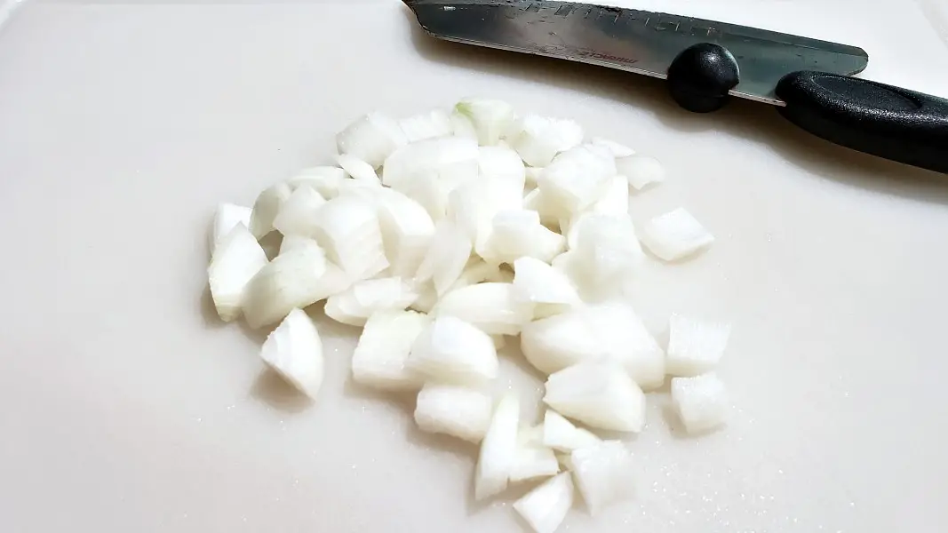 diced onions on a cutting board with chefs knife.