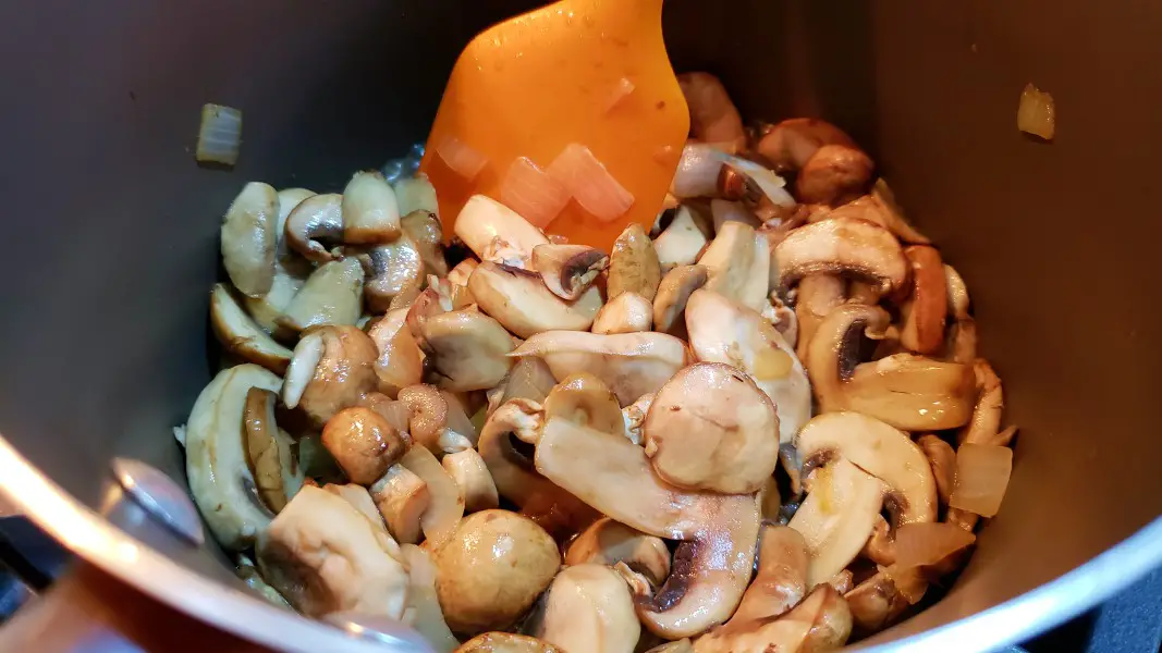 mushrooms and onions cooking in a sauce pan.