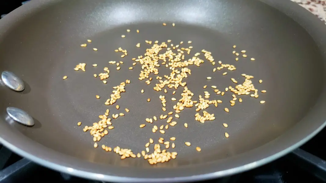 sesame seeds cooking in a dry frying pan.