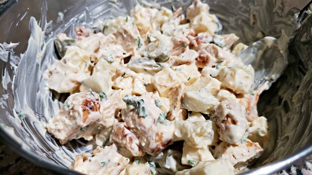 swiss cheese and dill pickle chicken salad mixed together in a bowl.