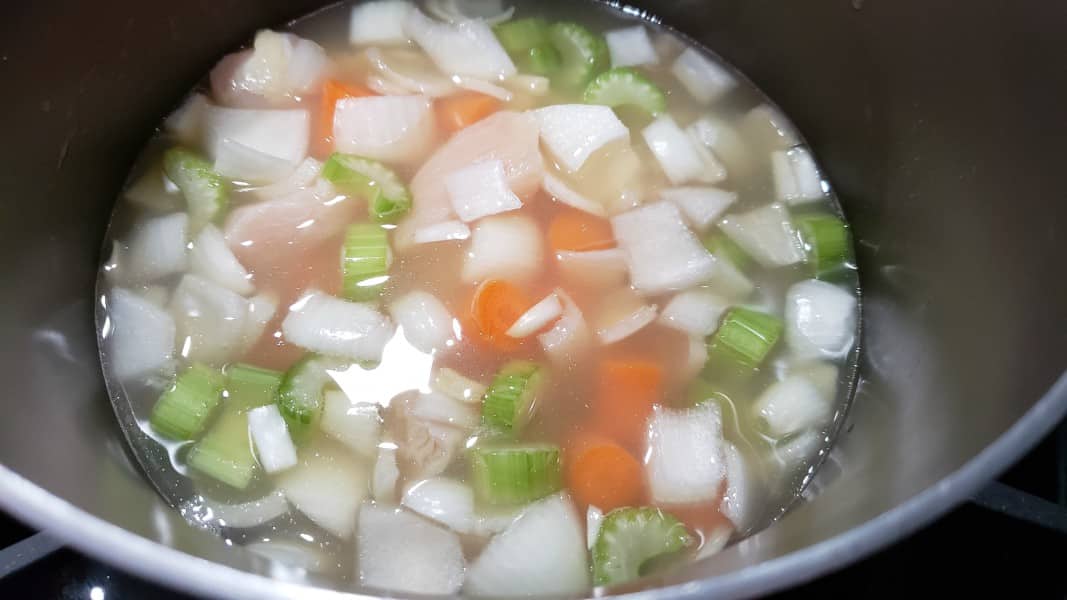 chicken, celery, onions, and carrots cooking in broth.