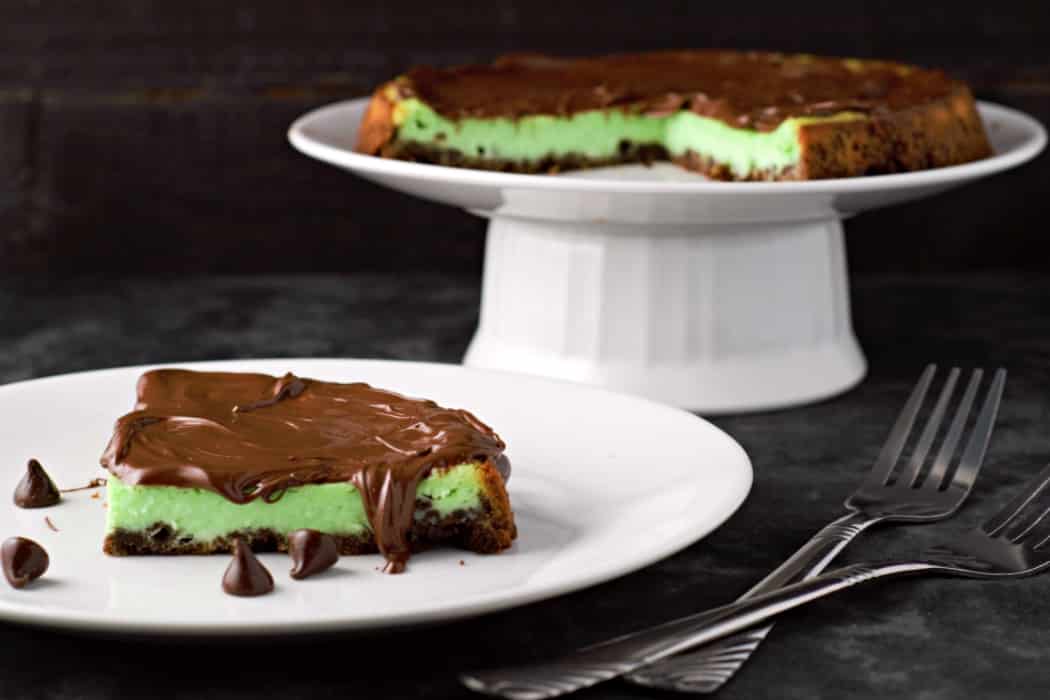 a slice of Mint Chocolate Tart on a plate and the rest of the mint cheesecake on a cake plate.