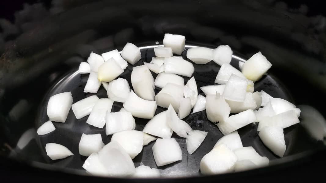 diced onions in a slow cooker crock pot.
