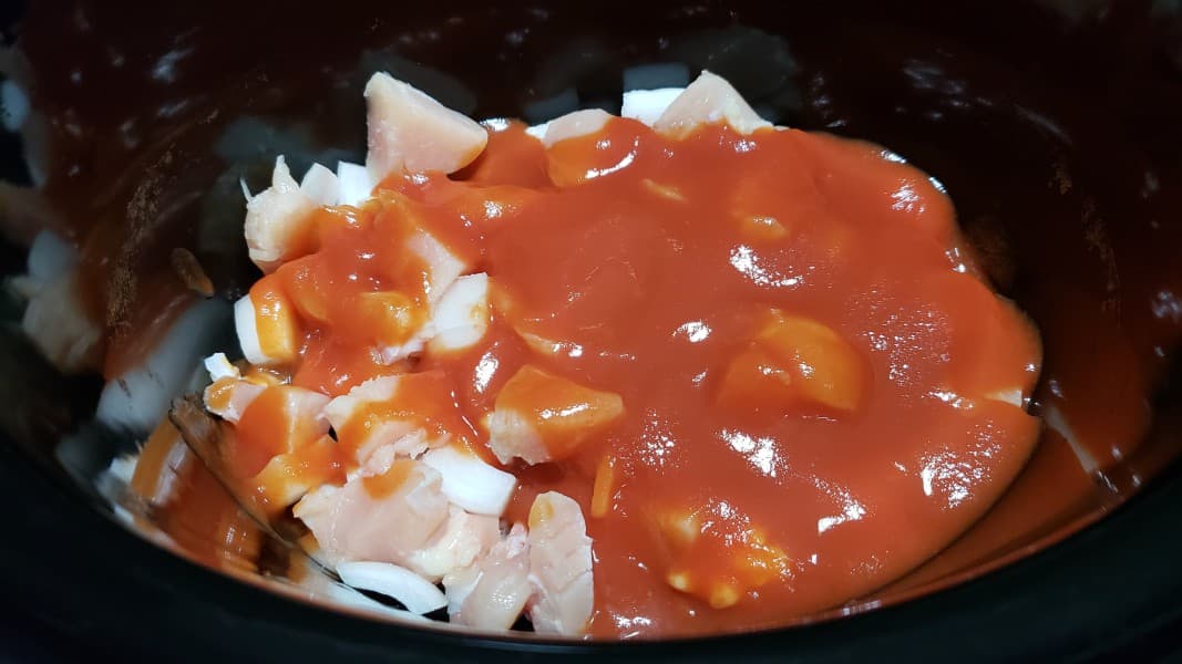 onions, chicken and tomato sauce in a slow cooker crock pot.